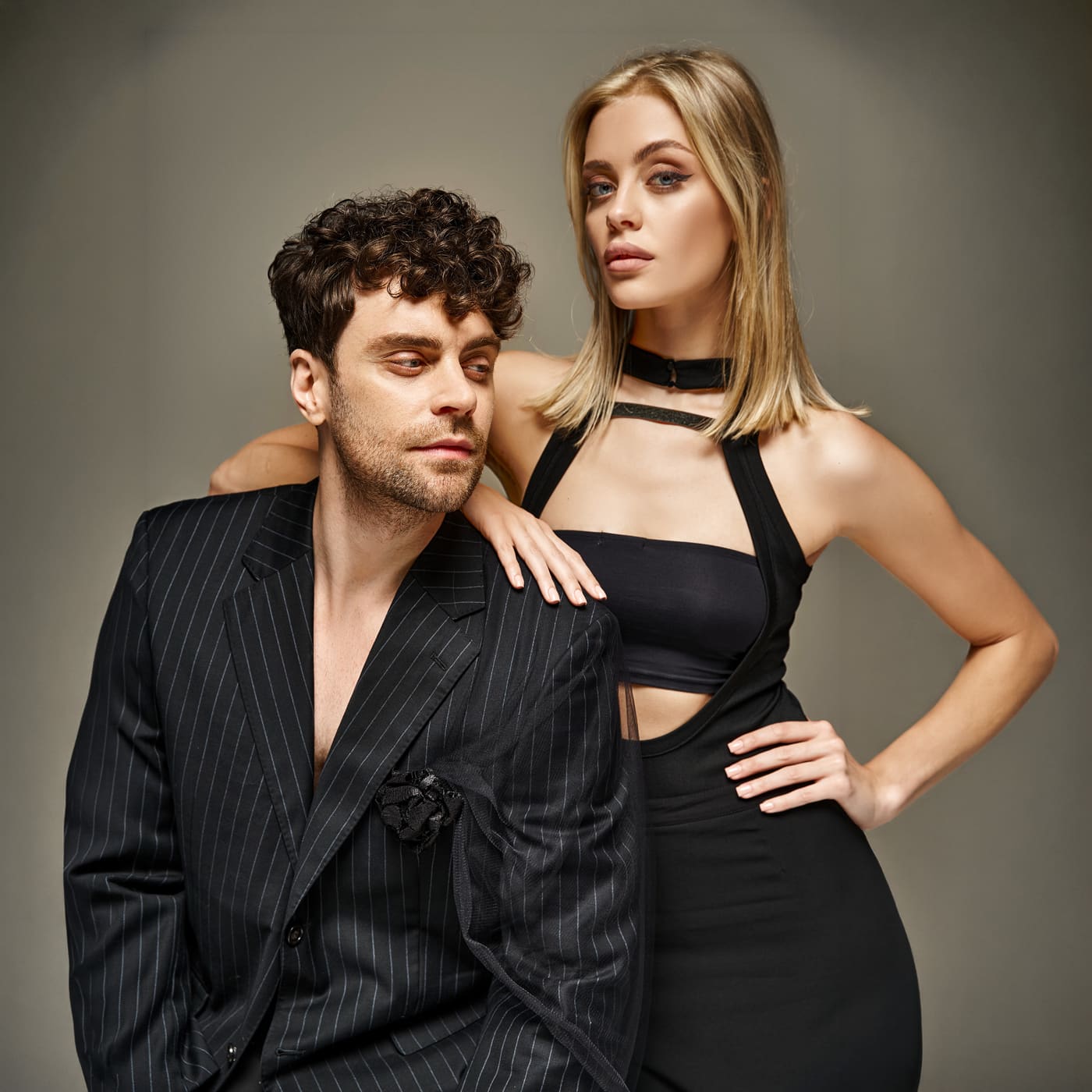 Man in a pinstripe suit beside a blonde woman in a black cut-out dress
