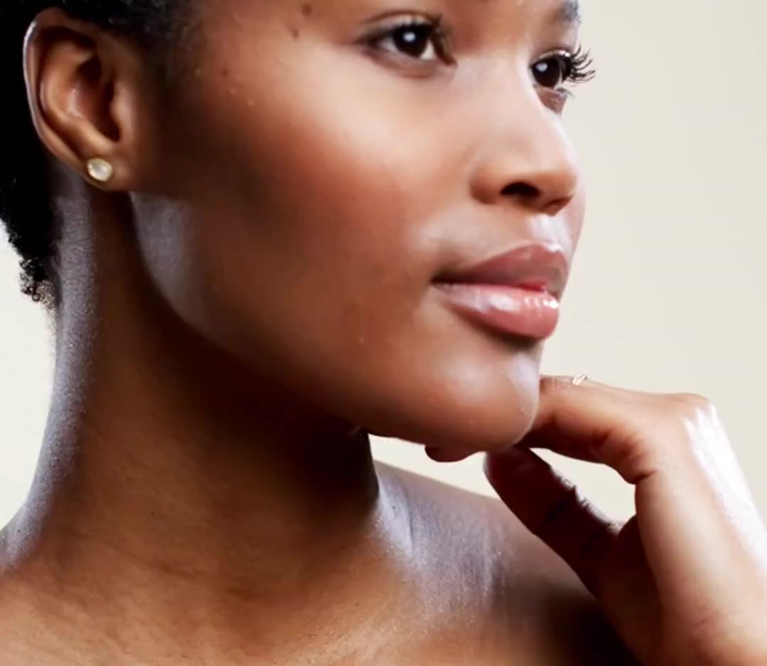 A woman with glowing, smooth skin resting her chin on her hand