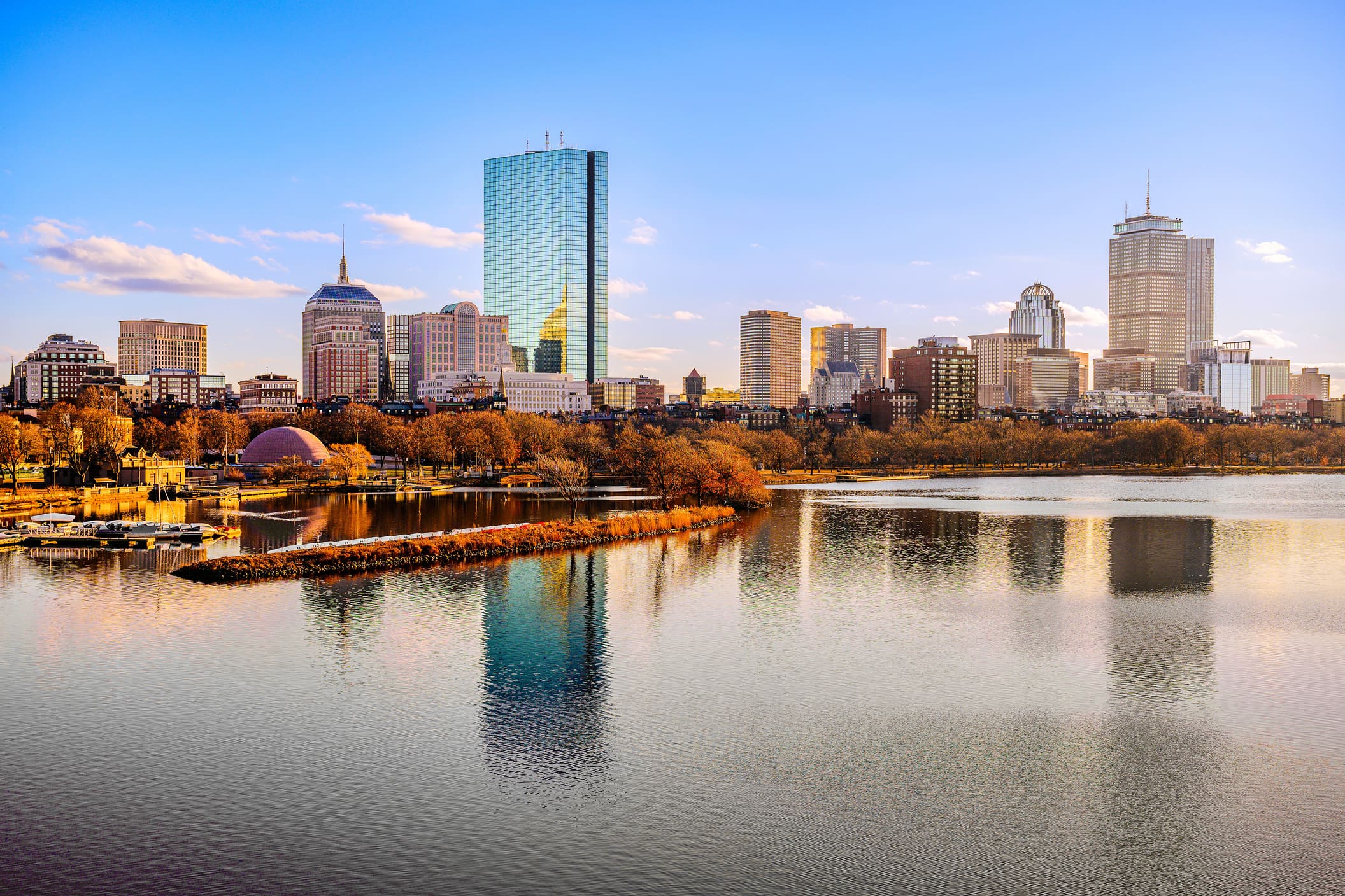 The Boston skyline over the Charles River at sunset, autumn trees along the Esplanade