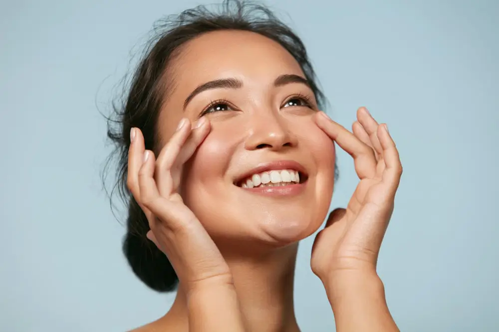 Smiling woman touching the side of her eye.